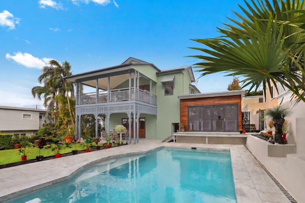 Two-story pool house with sage-green walls and a covered balcony